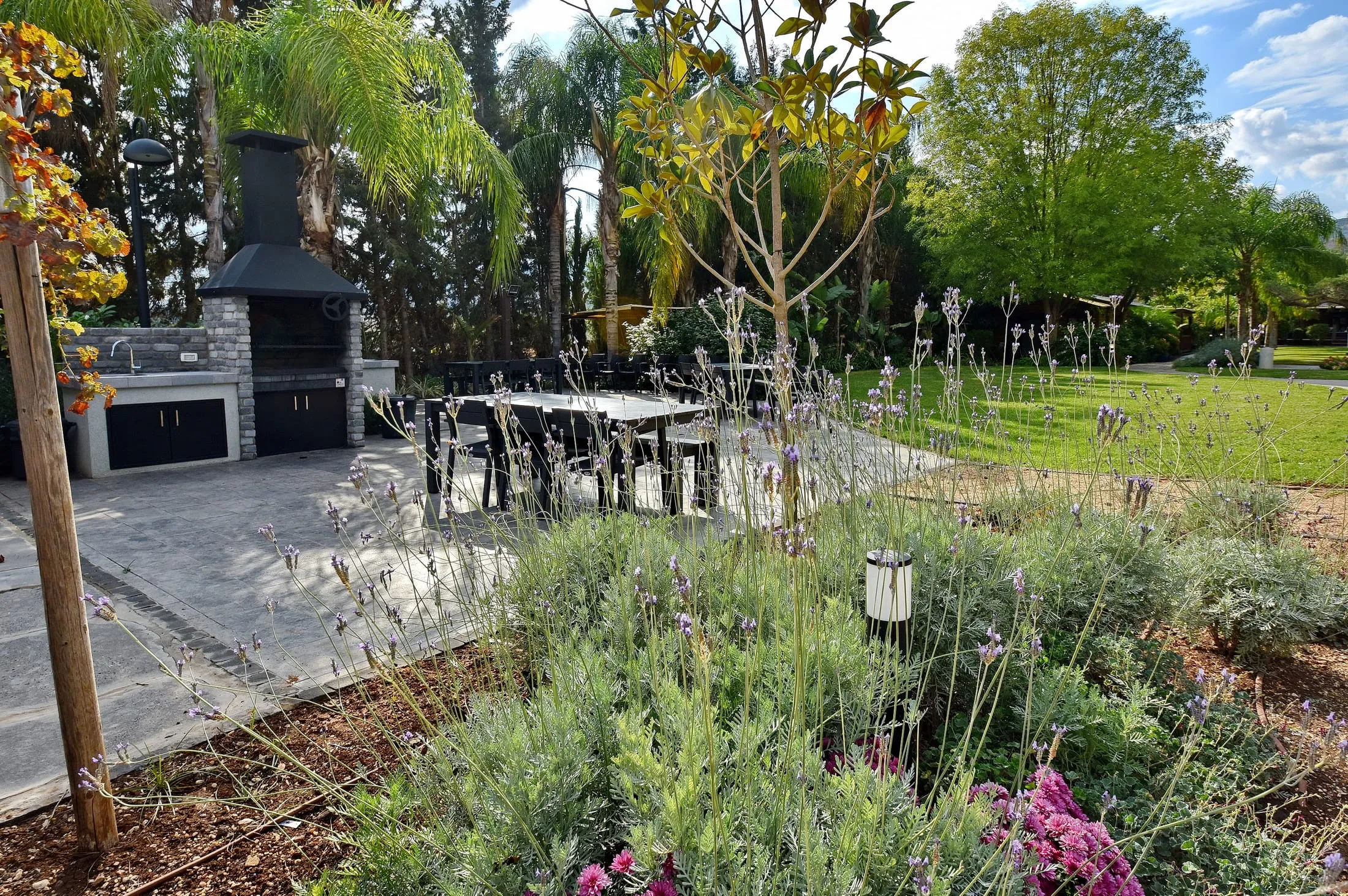 Lavender garden beds framing the BBQ area and outdoor dining table at Halomot Naftali resort
